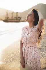 beautiful sexy girl in a dress walks on the beach against the background of ships.