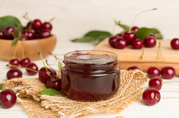 Jar with tasty homemade cherry jam on wooden table