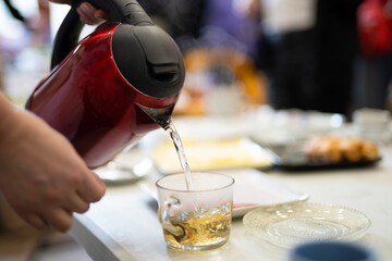 pouring boiling water from an electric kettle into a mug