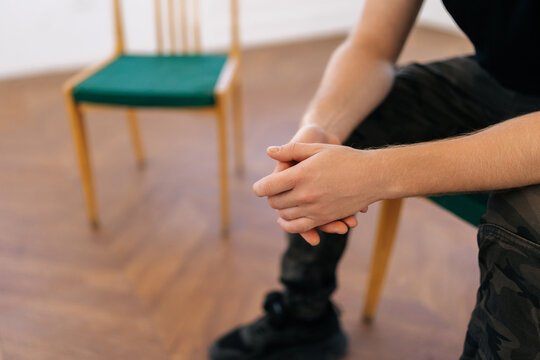 Closeup hands of unrecognizable nervous young man sharing traumatic experience at therapy meeting during group psychotherapy session. Concept of mental health, psychotherapy, depression, social issues
