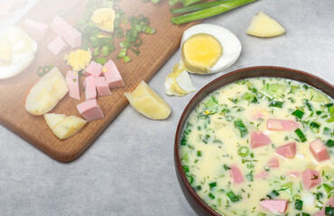 Summer cold soup okroshka with vegetables, sausage, herbs and kefir. Top view, close-up.