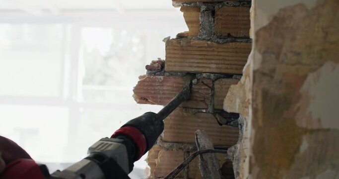 Close-up of the builder's hands dismantling the wall with a perforator. Repair in buildings and preparation for it. High quality 4k footage