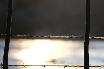 Freezing winter temperatures shows ice on farm barbed wire fence outdoors.