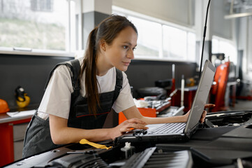 Back view on woman auto engineer doing computer diagnostic