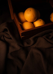 Creative photography of orange fruits, fresh orange fruit on a wooden basket isolated on brown colour fabric