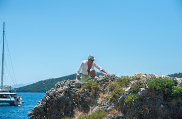 A tourist is trying to climb on the rock by the sea in Greece