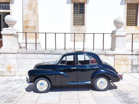 Black classic car on the background of an ancient European monastery. Vintage polished restored vehicle.