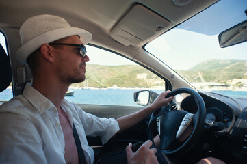 A young man is driving a car on the Greek island