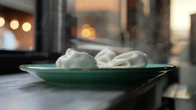 Khinkali freeze on the street. Hot khinkali on plates outside. National Georgian cuisine Khinkali. Khinkalia cool down on a plate.