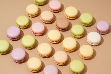 Fototapeta premium An overhead shot of a beige table surface featuring an array of colorful macarons in neat rows