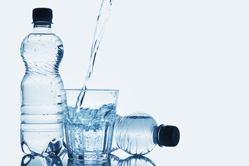 Blue bottles and pouring of pure still water into glass on white background
