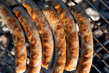 Cooking tasty Grilled juicy sausages at bbq grill backyard. grilling on charcoal. steaks on the grill. Roasting juicy sausages on hot charcoal. Grilling barbeque sausages on the grill outdoors