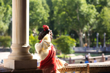 Young black woman dressed as a flamenco gypsy in a square in Seville, Spain. She wears a beige...