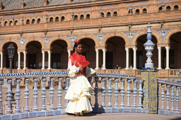 Young black woman dressed as a flamenco gypsy in a famous square in Seville, Spain. She wears a...