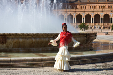 Young black woman dressed as a flamenco gypsy in a famous square in Seville, Spain. She is wearing...