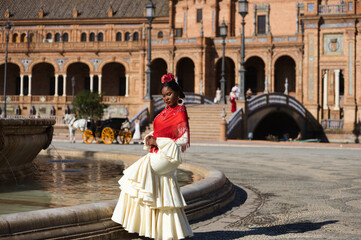 Young black woman dressed as a flamenco gypsy in a famous square in Seville, Spain. She is wearing...