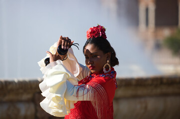 Young black woman dressed as a flamenco gypsy in a famous square in Seville, Spain. She is wearing...