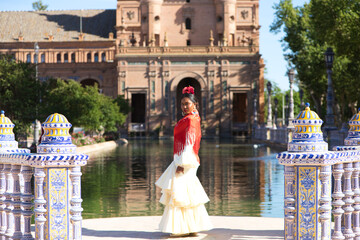 Young black woman dressed as a flamenco gypsy in a famous square in Seville, Spain. She is wearing...