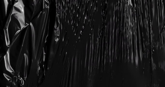 Experience tactile allure of a stretched plastic film texture against deep black canvas, echoing the delightful crinkles folds reminiscent of rumpled cellophane wrap commonly found in food packaging.