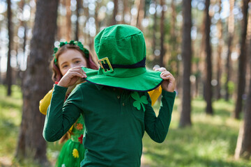 Happy kids celebrating St Patricks Day in the forest. Children dressed as a pixie and a leprechaun...