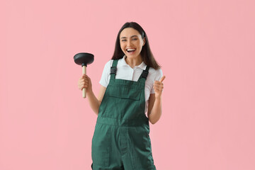 Happy female plumber with plunger showing thumb-up on pink background