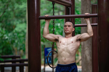 Handsome man exercises by hanging on a bar outdoor, Asian man trains for sporting events