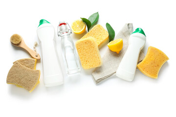 Bottles of vinegar, detergents, lemons, brush and sponges on white background