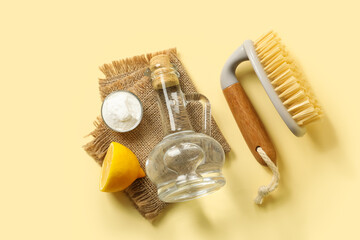 Jug of vinegar, baking soda, brush, lemon and napkin on color background