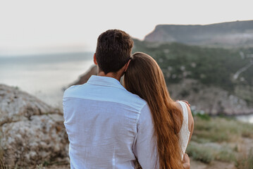 Beautiful young loving couple man of Middle Eastern appearance and a Caucasian woman hug, kiss at sunrise.