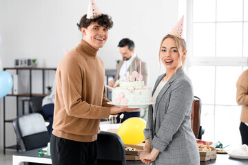 Young man greeting his colleague with Birthday cake at party in office