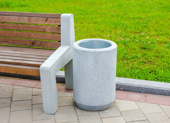Garbage concrete, stone bin in a public park next to a bench. Garbage bin in the park.