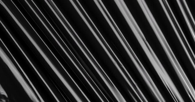 Discover an otherworldly fusion of textures as stretched plastic film weaves across a black expanse, resembling a whimsical dance of crinkled cellophane wrap, conjuring a sense of magic and intrigue.