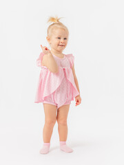 Choice. A 2-year-old toddler girl in a pink dress shows 1 finger and smiles on a white background.