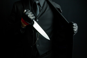 Portrait of Mystery Man in Black Suit Pulling Out Knife From Jacket. Horror Movie Killer.