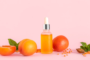 Composition with bottle of essential oil, ripe apricots and mint leaves on pink background