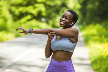 Active and fit young woman stretching her arms while exercising outdoors. Determined African...