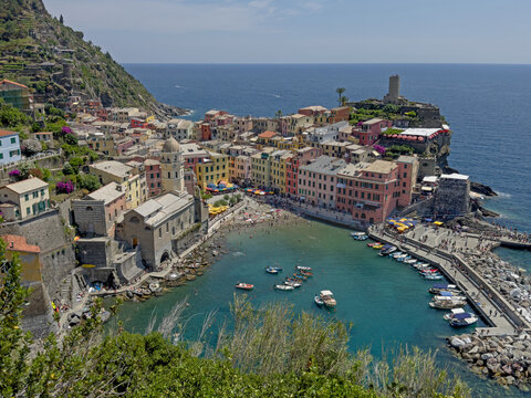 The colorful village of Vernazza, with its marina in the foreground, is shown with the Gulf of Genoa in the background during the day. This is one of the villages in Italys famed Cinque Terre region.