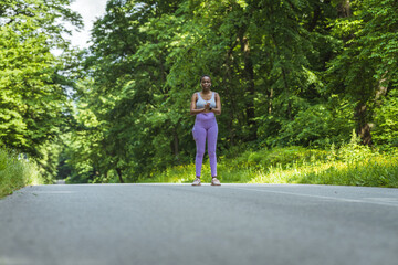 Strong athletic black woman sprinting during workout while listening to music with earphones.