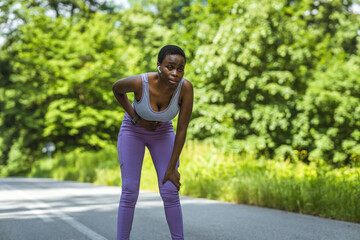 Exhausted woman, runner athlete in tight sportswear, putting her hands on her stomach, feeling...