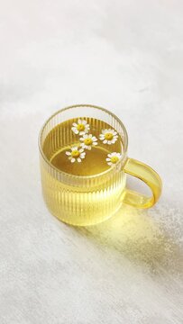 A cup of Chamomile tea on light wooden table with flowers 