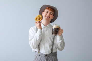 Young man in traditional German clothes with beer and pretzel on light background