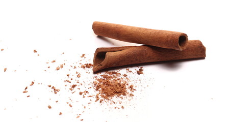 Cinnamon sticks, pieces with shavings in wooden spoon isolated on white, top view