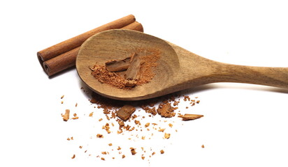 Cinnamon sticks, pieces with shavings in wooden spoon isolated on white, top view
