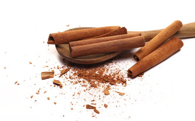 Cinnamon sticks, pieces with shavings in wooden spoon isolated on white, top view