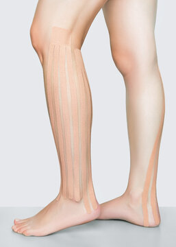 female legs with beige kinesio tapes. lymphatic drainage foot taping