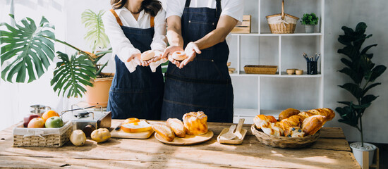 Young happy couple is enjoying and preparing healthy meal in their kitchen and reading recipes on the laptop.