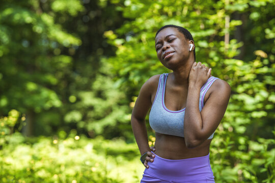 Shot of a sporty young woman holding her neck in pain while exercising outdoors.
