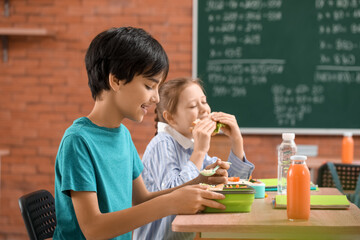 Little pupils having lunch in classroom