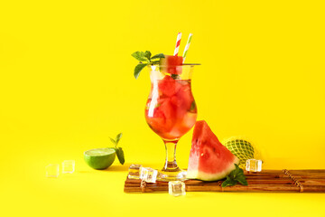 Glass of fresh watermelon lemonade with lime and mint on yellow background