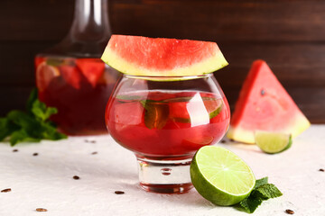 Glass and bottle of fresh watermelon lemonade with lime on white table